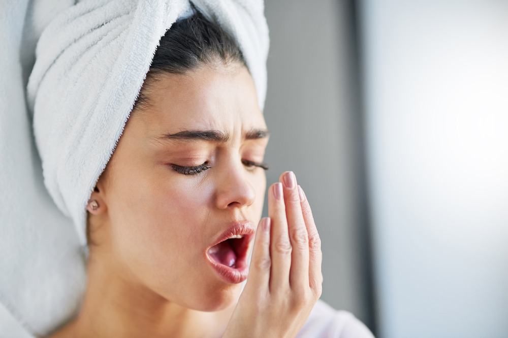 Woman checking her breath with a concerned expression