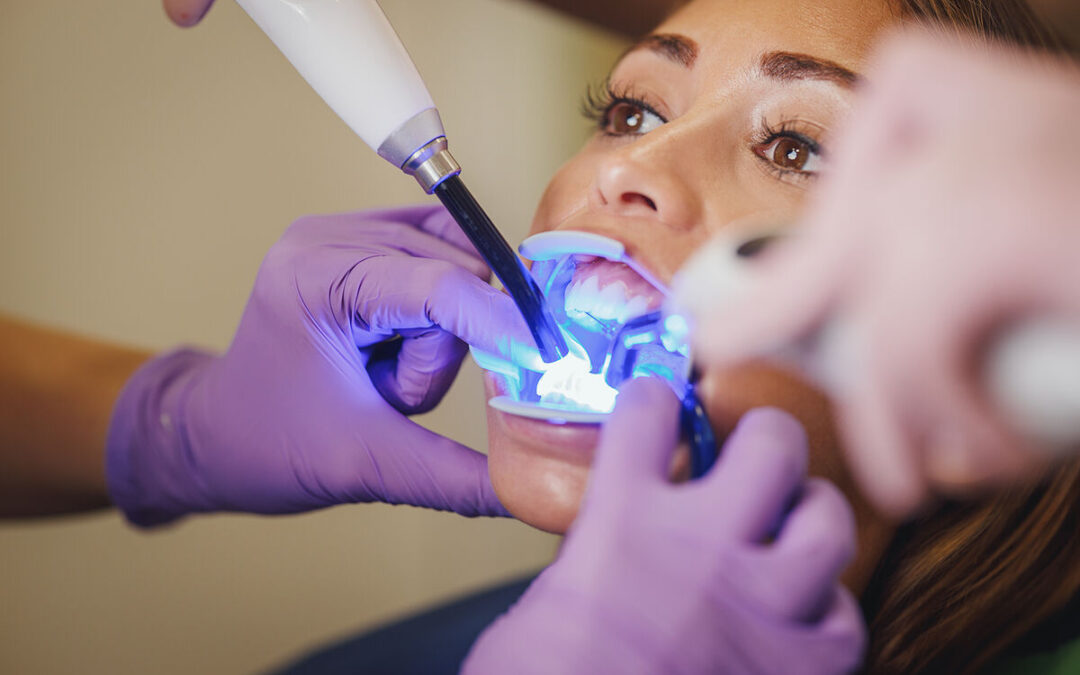 A woman receiving professional teeth whitening treatment with LED light technology at a cosmetic dentistry clinic.